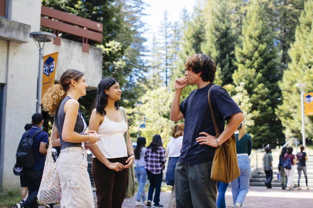 Students talking after class outside with trees in the background.